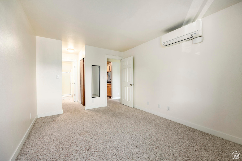 Empty room with an AC wall unit and carpet floors