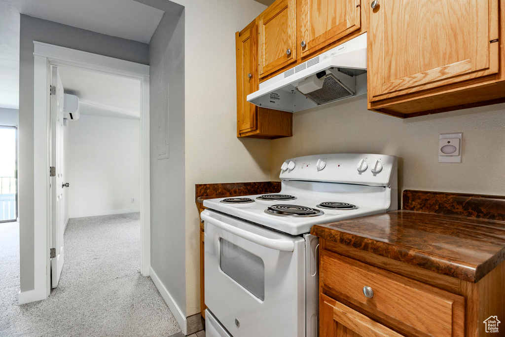 Kitchen with light colored carpet, a wall unit AC, and electric stove