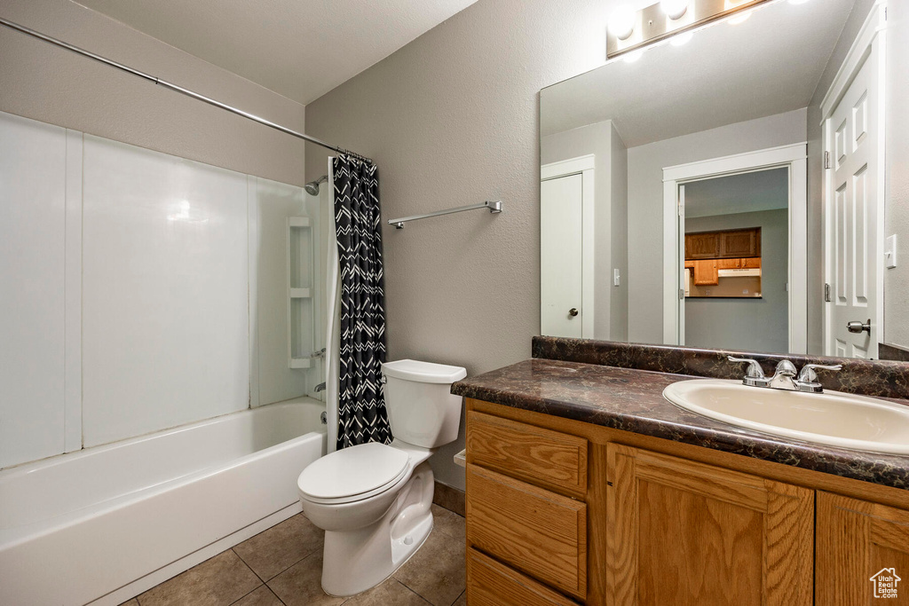 Full bathroom with tile flooring, shower / bath combination with curtain, toilet, and vanity