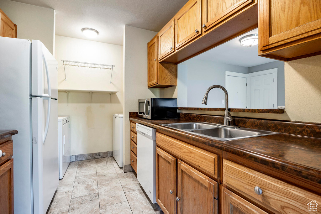 Kitchen with white appliances, sink, separate washer and dryer, and light tile floors