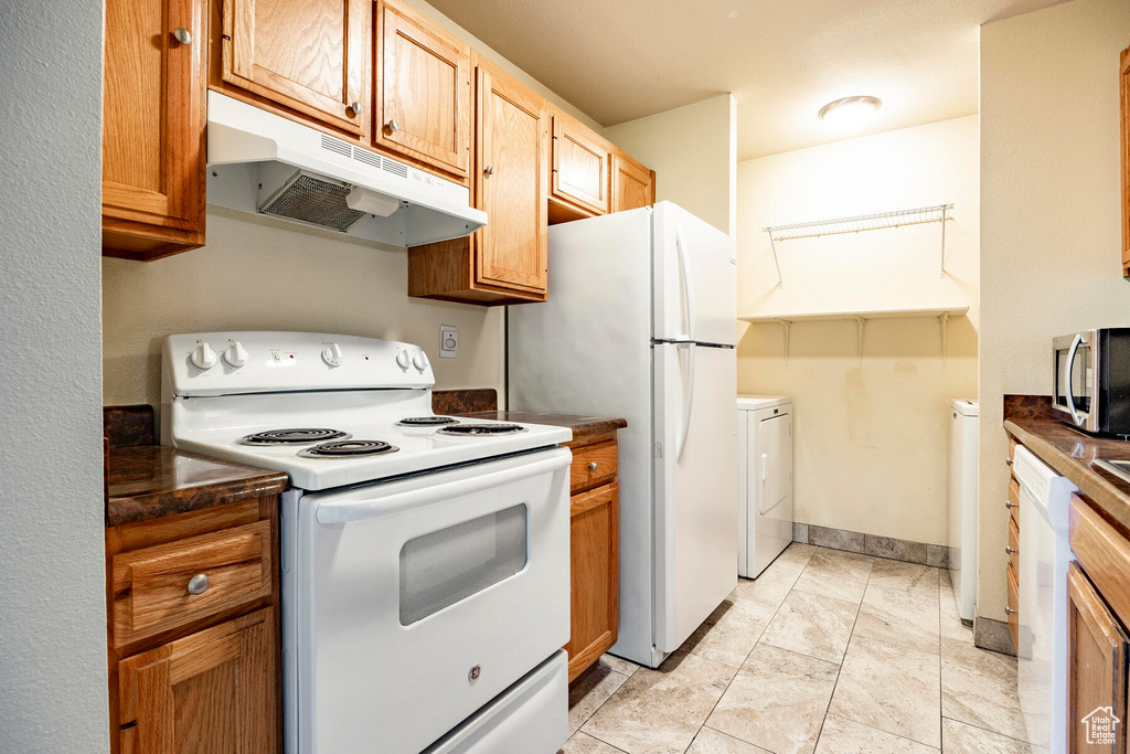 Kitchen featuring white appliances, separate washer and dryer, and light tile floors