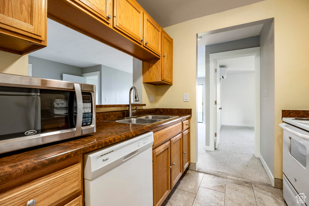 Kitchen with white appliances, sink, and light colored carpet