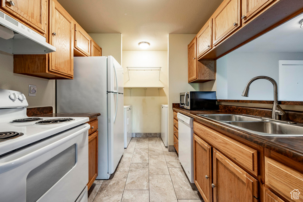 Kitchen featuring independent washer and dryer, sink, white appliances, and light tile flooring