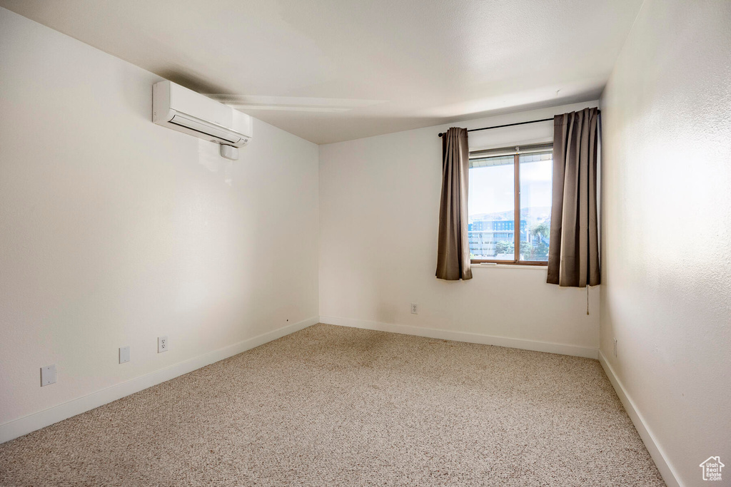 Carpeted spare room with a wall unit AC