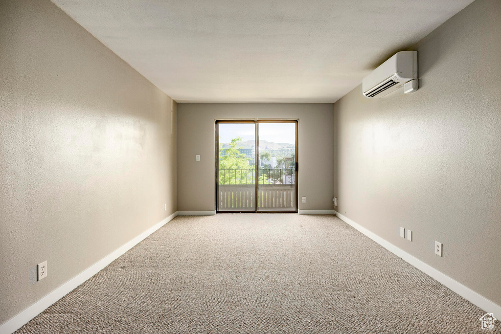 Carpeted spare room featuring an AC wall unit