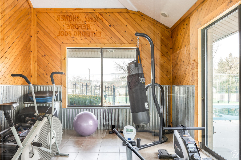 Workout area featuring a wealth of natural light, wood walls, tile flooring, and lofted ceiling