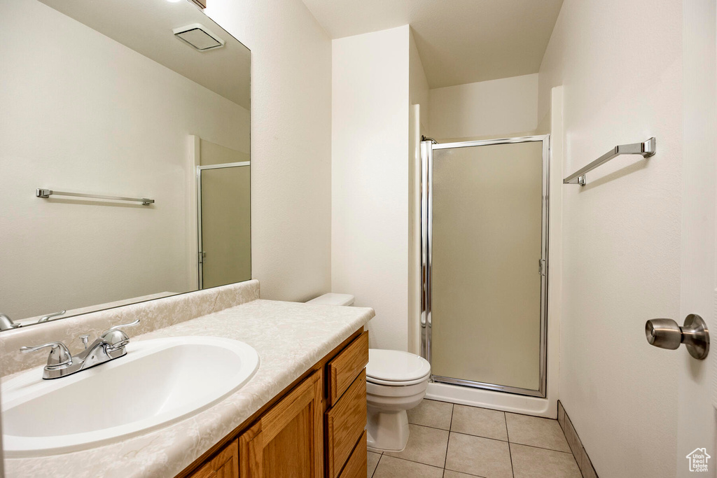 Bathroom featuring tile floors, a shower with door, large vanity, and toilet