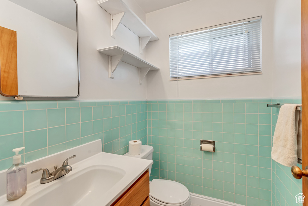 Bathroom with tasteful backsplash, tile walls, toilet, and large vanity