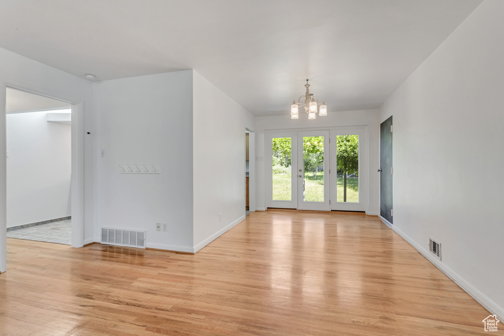 Empty room featuring a chandelier and light wood-type flooring