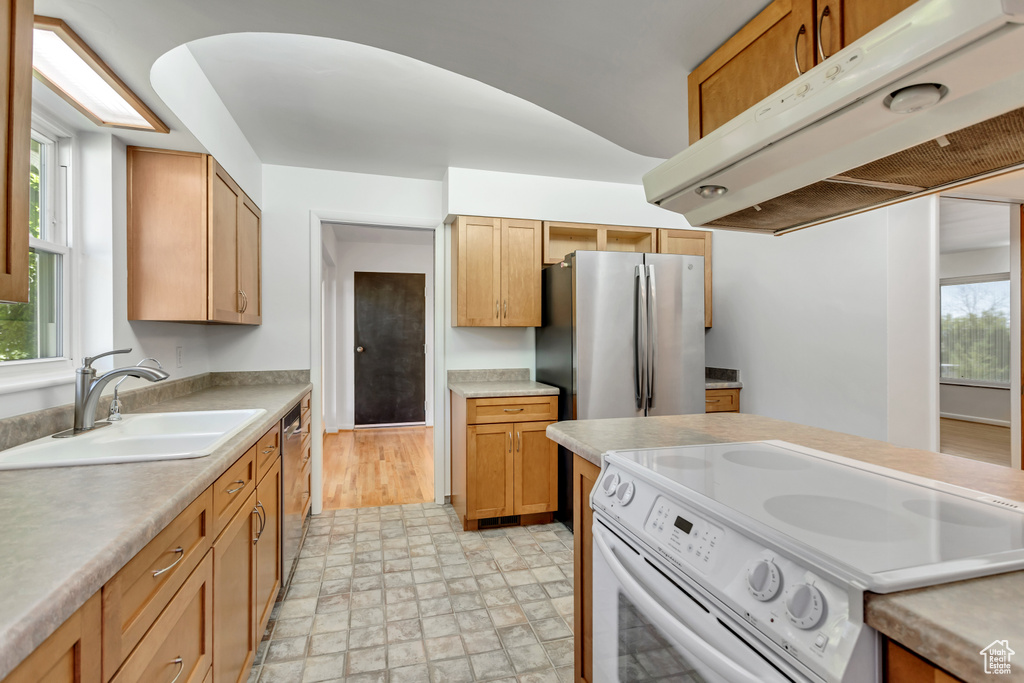 Kitchen with appliances with stainless steel finishes, sink, light tile floors, and plenty of natural light