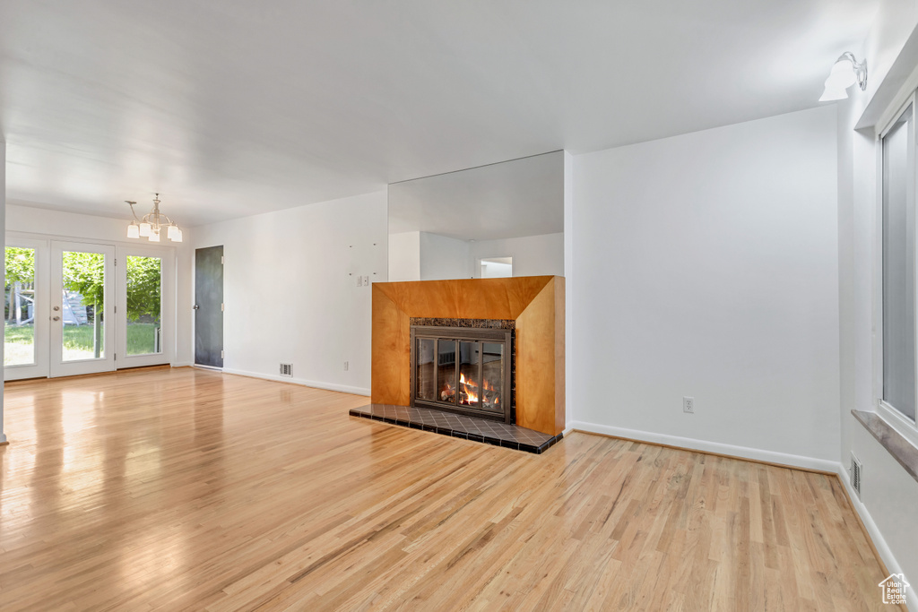 Unfurnished living room with an inviting chandelier and light wood-type flooring