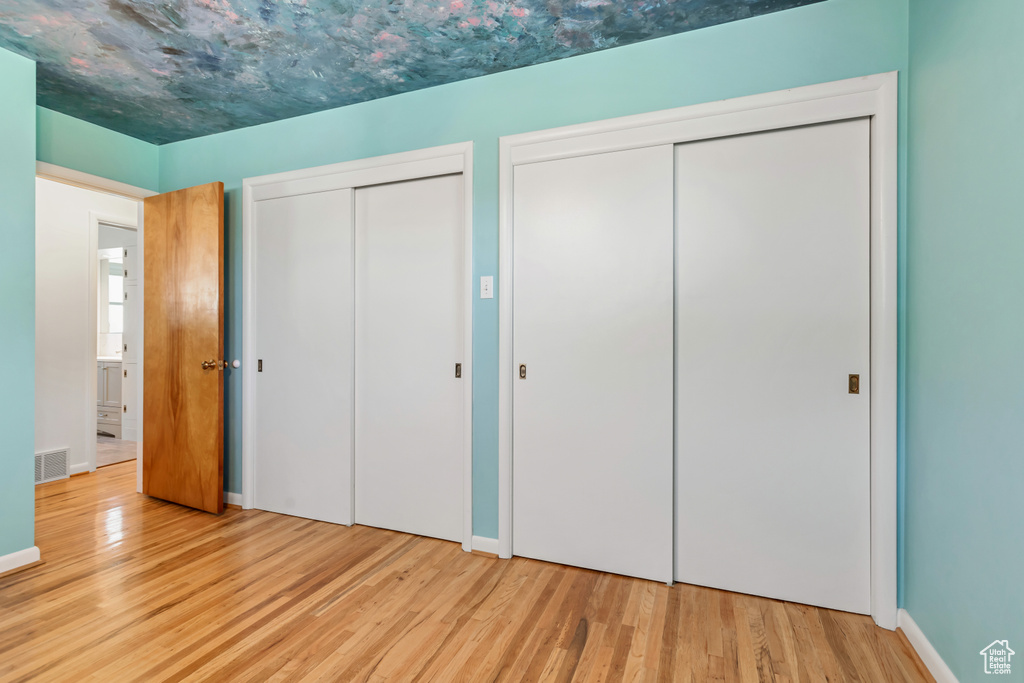 Unfurnished bedroom featuring two closets and light wood-type flooring