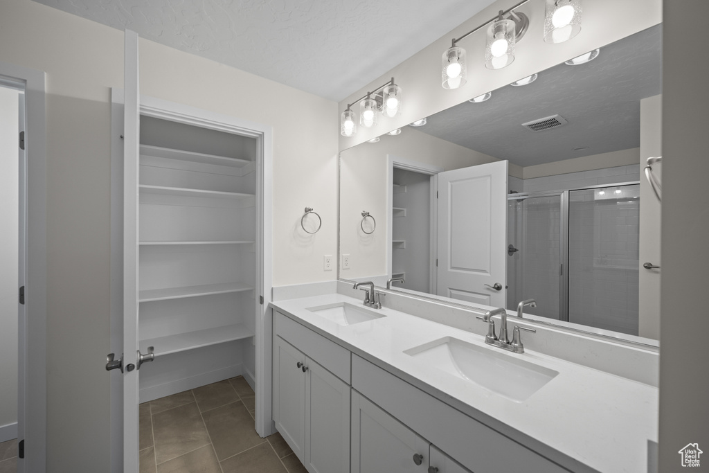 Bathroom with vanity, a shower with shower door, tile patterned flooring, and a textured ceiling