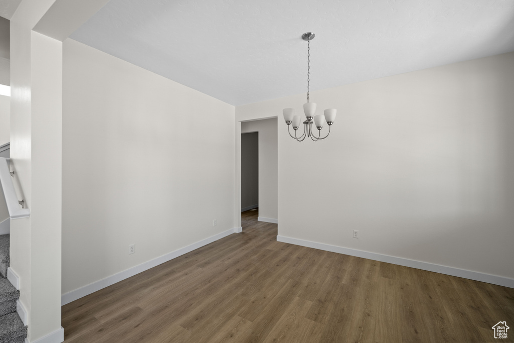 Unfurnished dining area with dark hardwood / wood-style floors and a notable chandelier