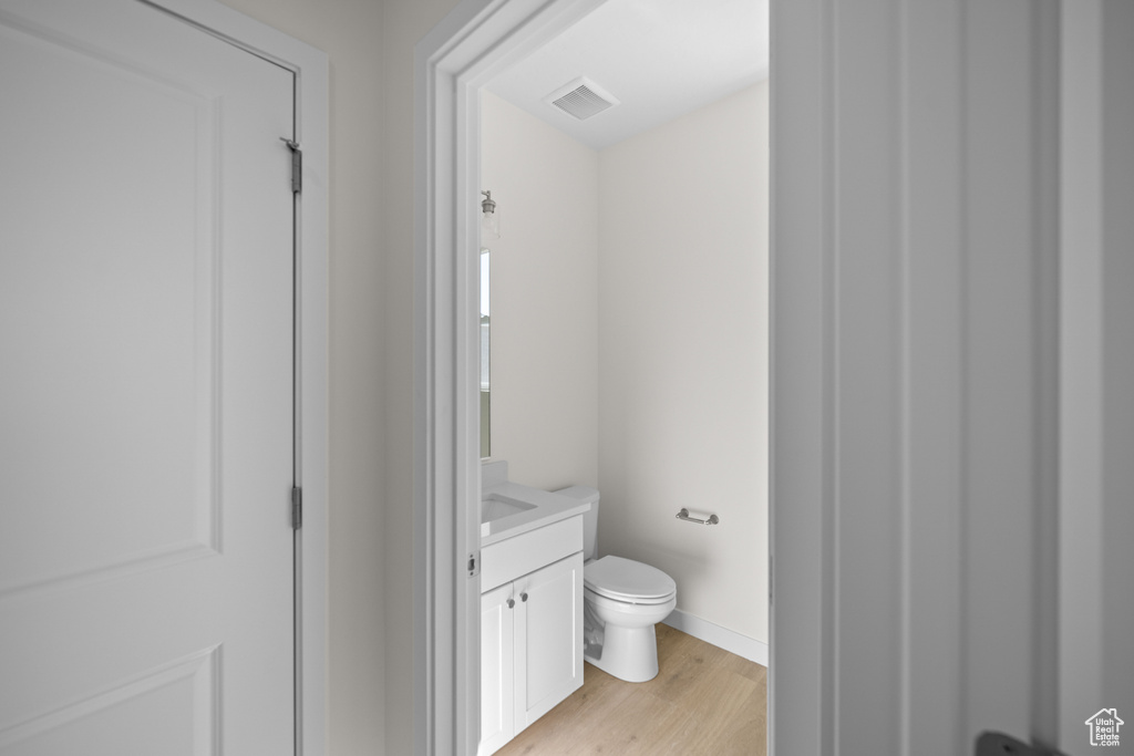 Bathroom featuring hardwood / wood-style floors, vanity, and toilet