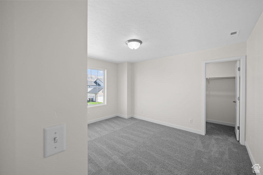 Unfurnished bedroom with a spacious closet, a closet, and carpet