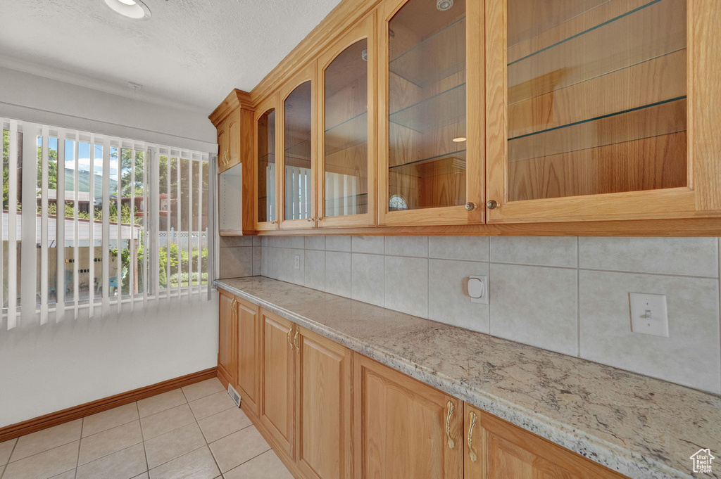 Interior space featuring light stone countertops, tasteful backsplash, and light tile floors