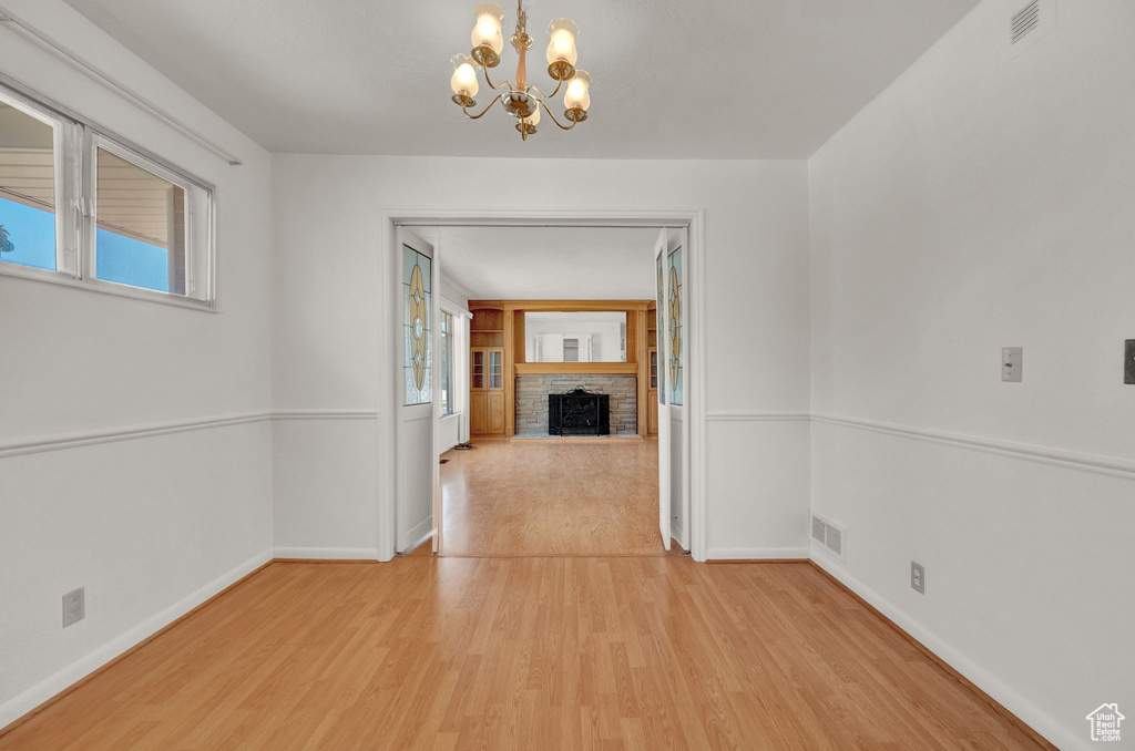 Interior space featuring a notable chandelier, a stone fireplace, and light hardwood / wood-style floors