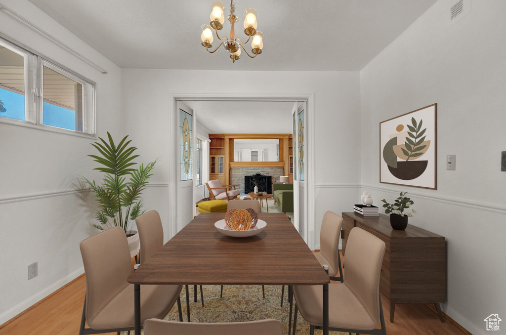 Dining area with a fireplace, hardwood / wood-style floors, and a chandelier