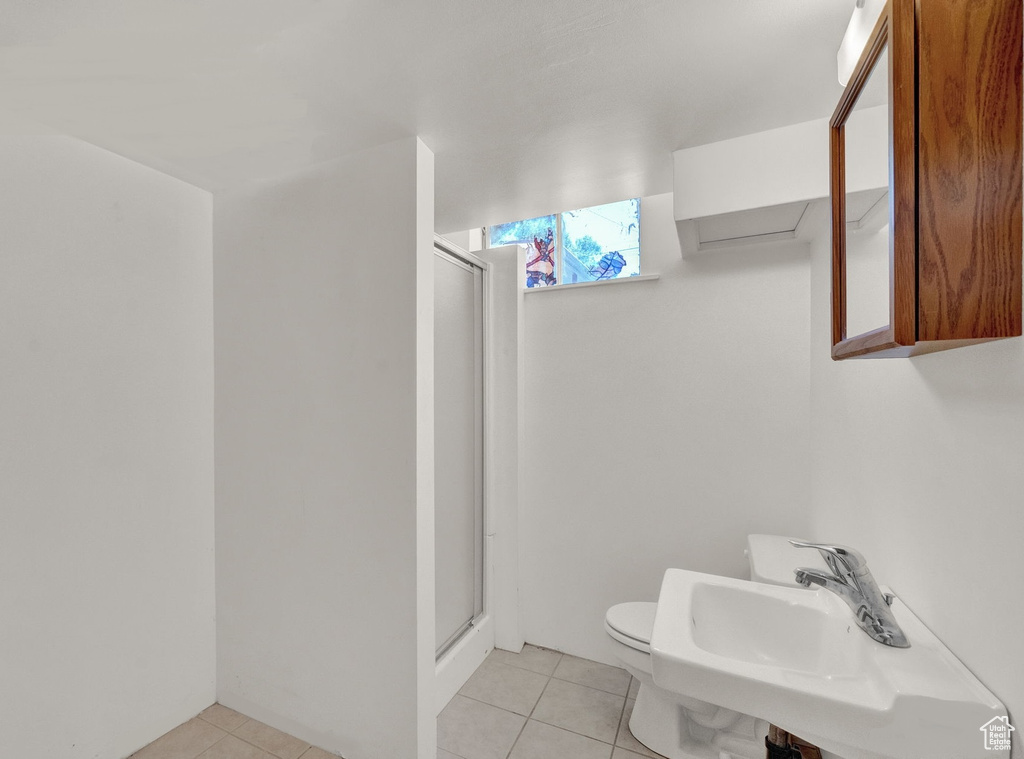 Bathroom with tile patterned flooring, toilet, sink, and an enclosed shower