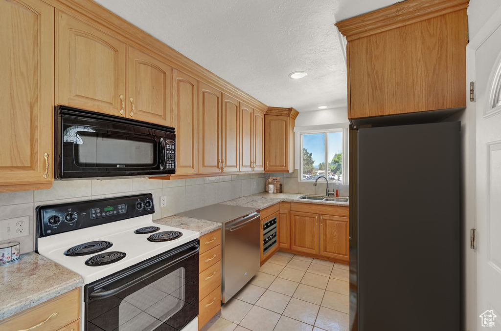 Kitchen with black appliances, tasteful backsplash, light brown cabinets, sink, and light tile patterned floors