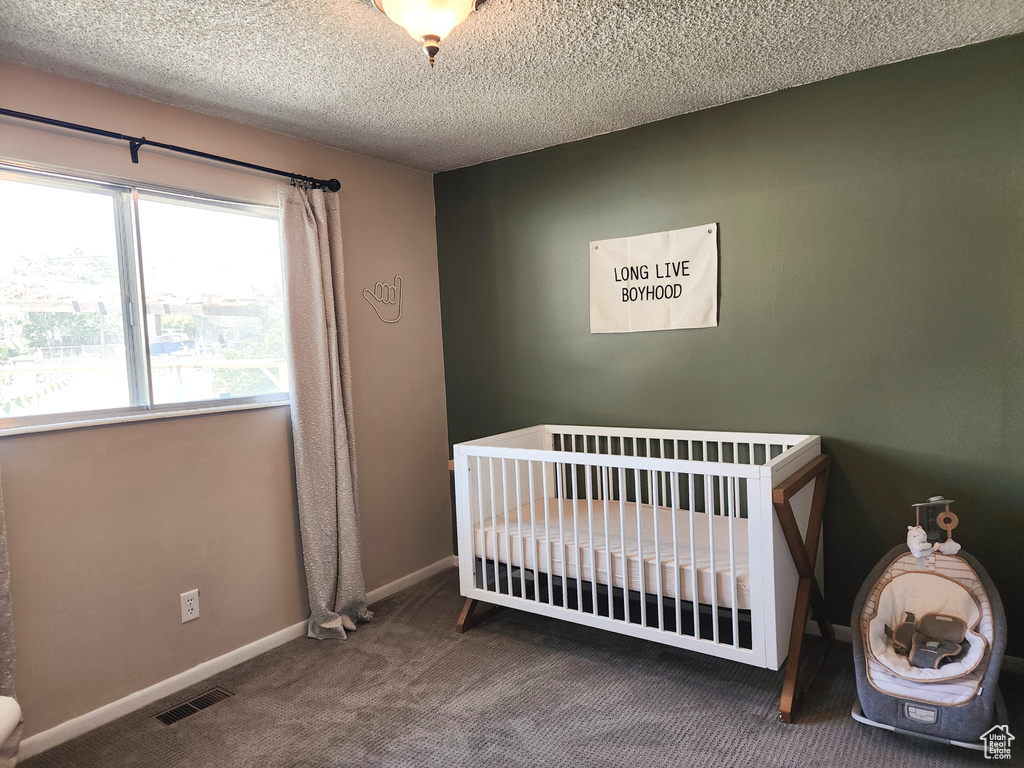 Carpeted bedroom with a nursery area and a textured ceiling