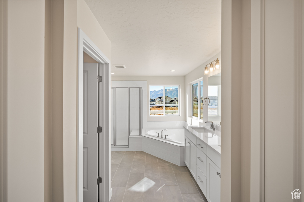 Bathroom featuring vanity, tile patterned flooring, a textured ceiling, and separate shower and tub