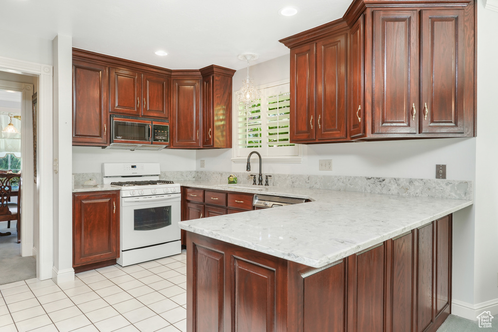 Kitchen with kitchen peninsula, gas range gas stove, dishwasher, light tile floors, and sink