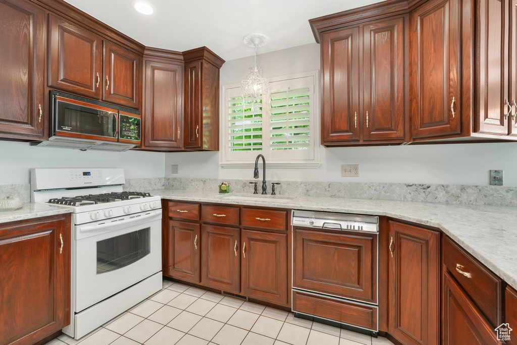 Kitchen featuring gas range gas stove, decorative light fixtures, dishwasher, sink, and light tile floors