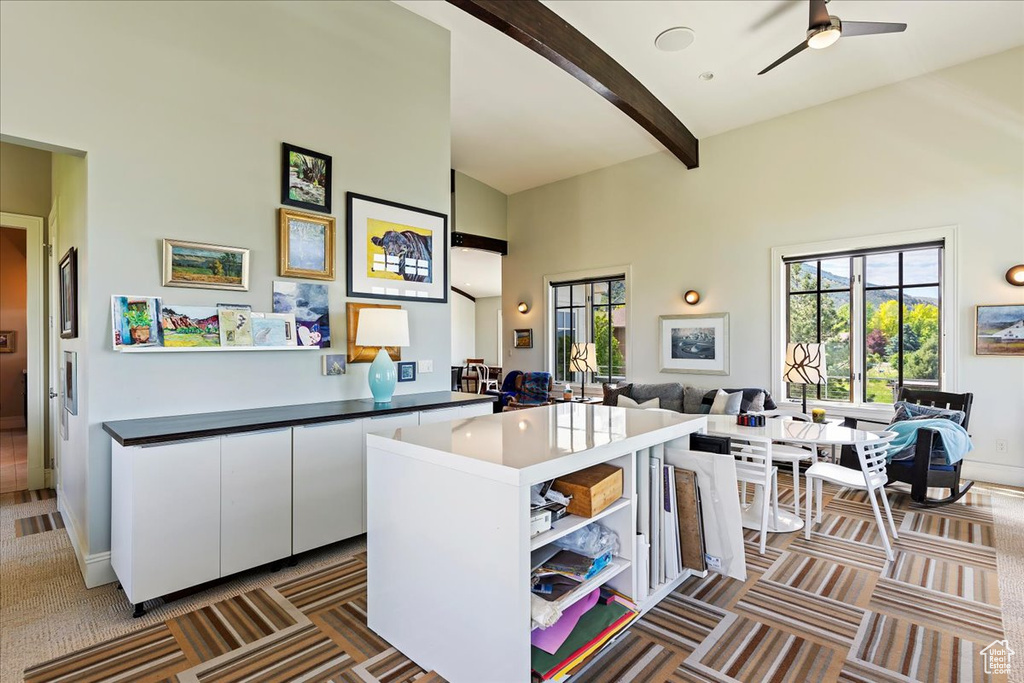 Kitchen featuring beamed ceiling, white cabinets, high vaulted ceiling, carpet flooring, and ceiling fan