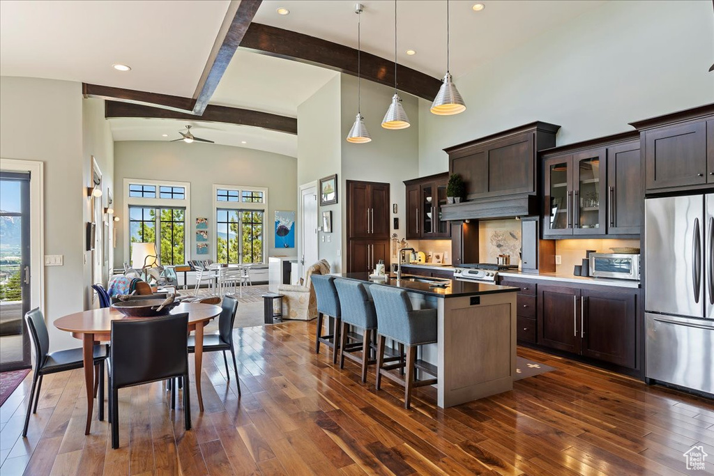 Kitchen with ceiling fan, stainless steel appliances, a center island with sink, lofted ceiling with beams, and dark hardwood / wood-style flooring