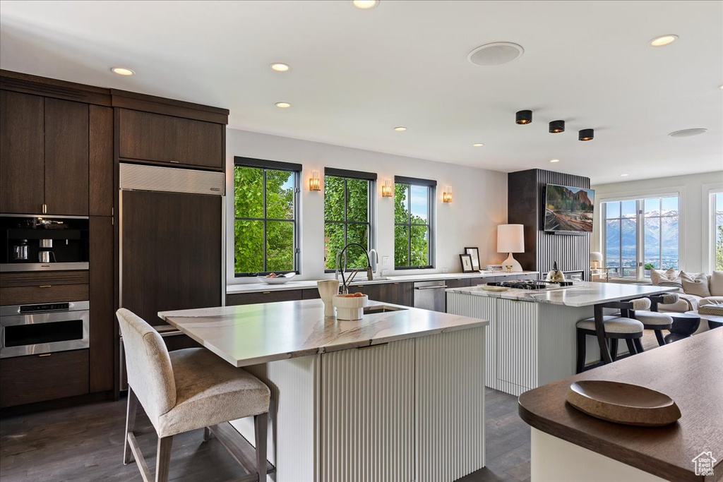 Kitchen featuring a breakfast bar area, a kitchen island, dark brown cabinetry, and dark hardwood / wood-style flooring