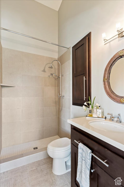 Bathroom featuring tiled shower, tile flooring, vanity, and toilet