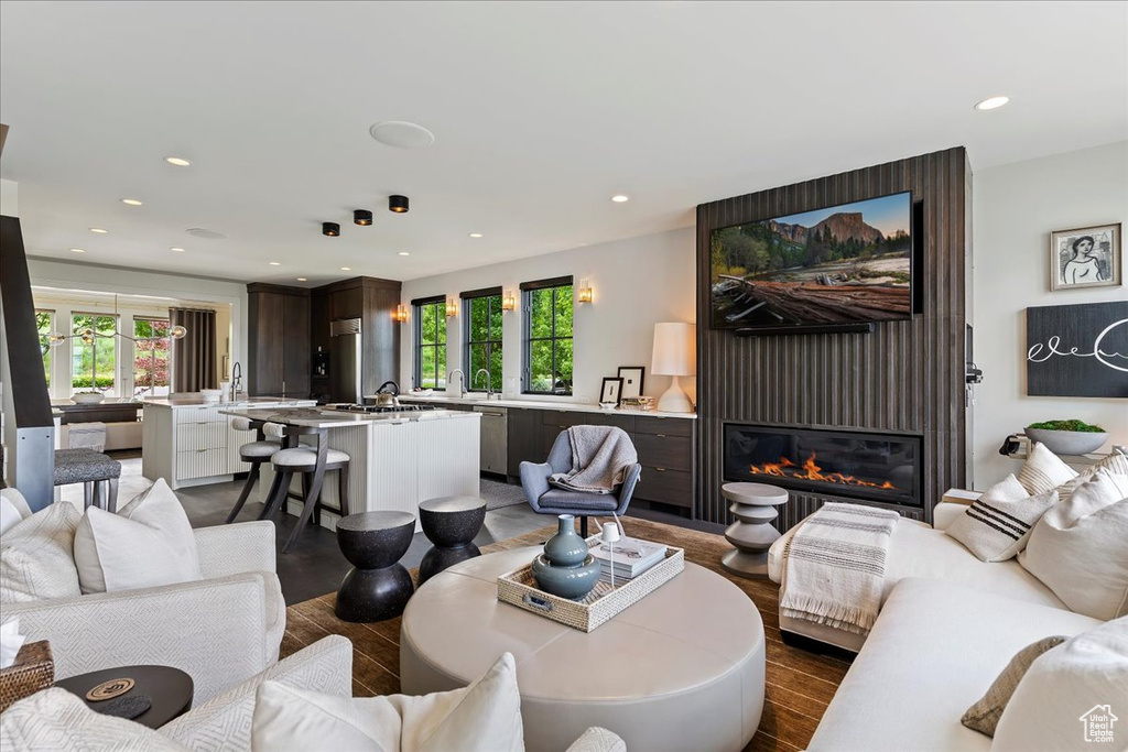 Living room featuring a wealth of natural light, a large fireplace, sink, and hardwood / wood-style flooring