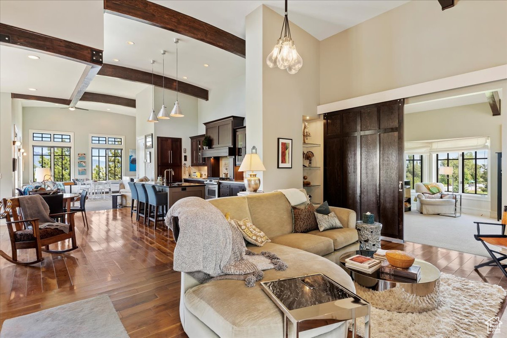 Living room with beamed ceiling, plenty of natural light, a chandelier, and hardwood / wood-style flooring