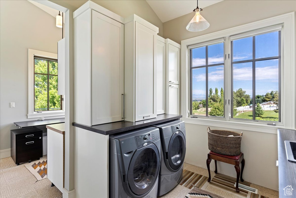 Laundry room with light carpet, a healthy amount of sunlight, separate washer and dryer, and cabinets