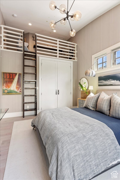 Bedroom with hardwood / wood-style flooring and an inviting chandelier