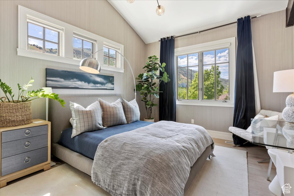 Bedroom with lofted ceiling, multiple windows, and hardwood / wood-style floors