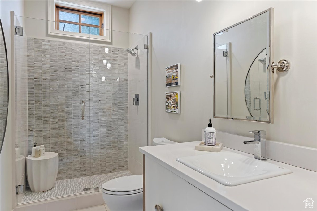 Bathroom featuring a shower with shower door, toilet, and large vanity