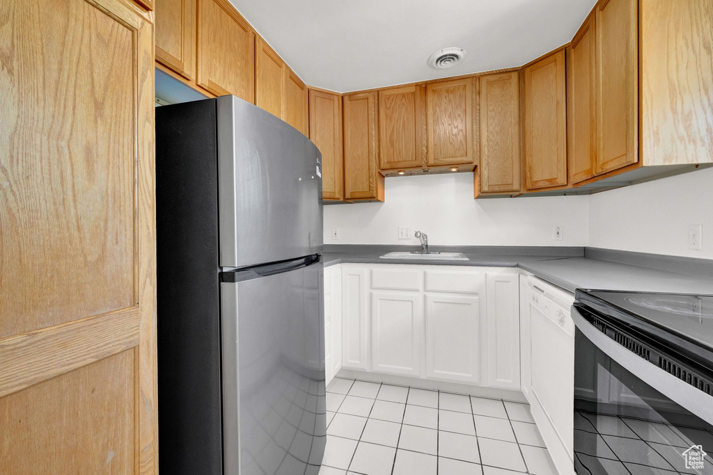 Kitchen with range with electric stovetop, stainless steel fridge, white dishwasher, sink, and light tile floors