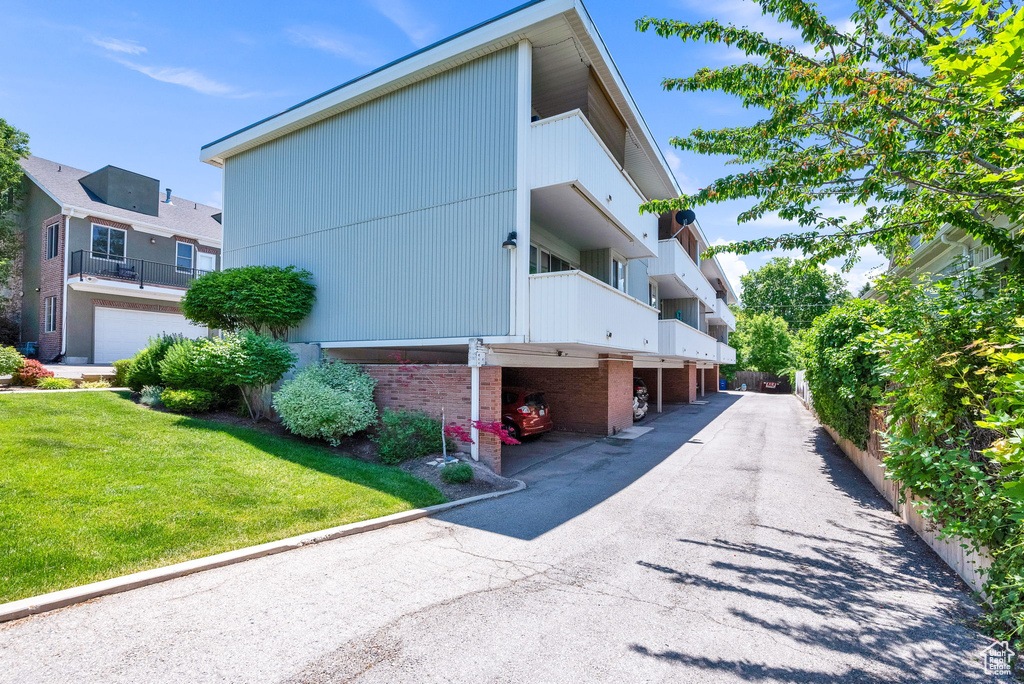 View of property exterior featuring a lawn and a balcony