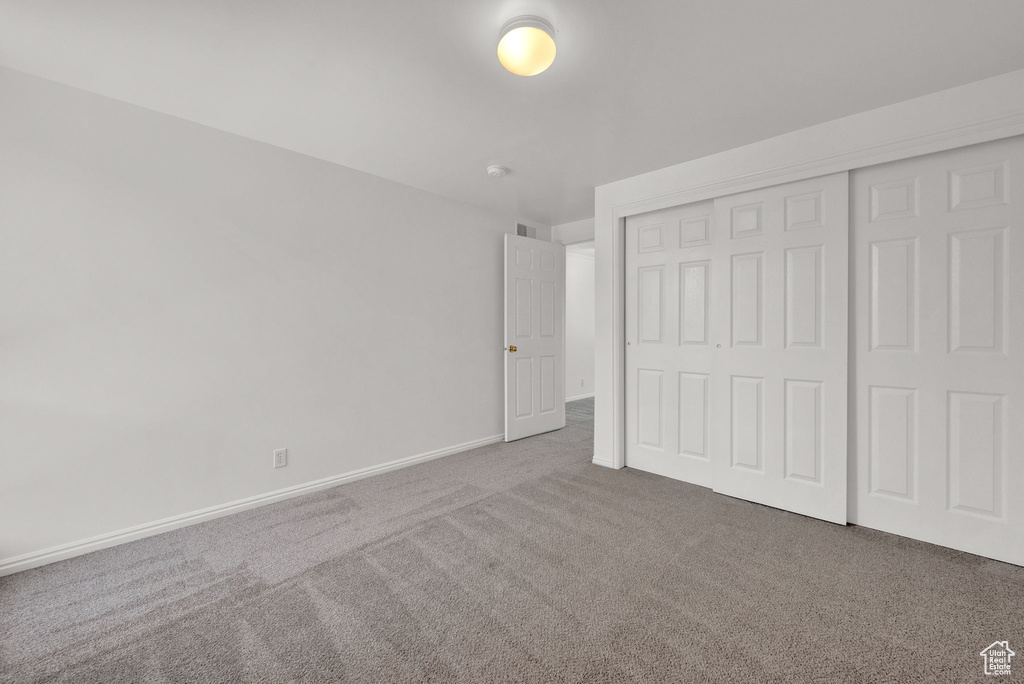 Unfurnished bedroom with a closet and dark colored carpet