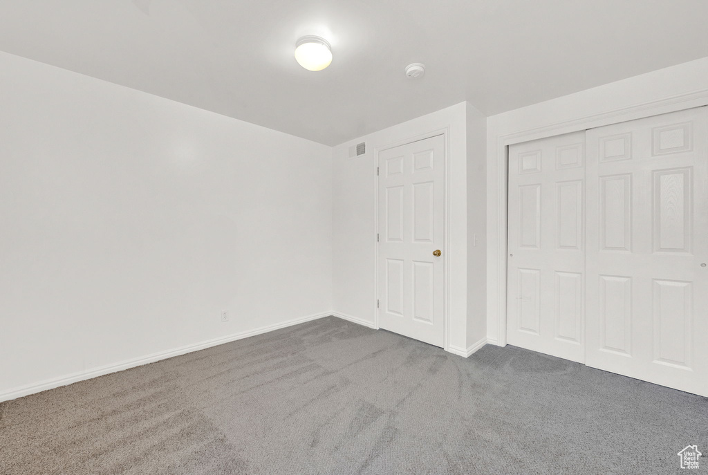 Unfurnished bedroom featuring dark carpet and a closet