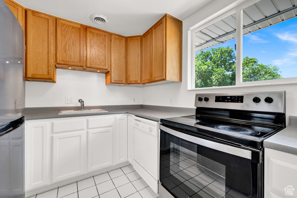 Kitchen with dishwasher, stainless steel electric range oven, range, sink, and light tile floors