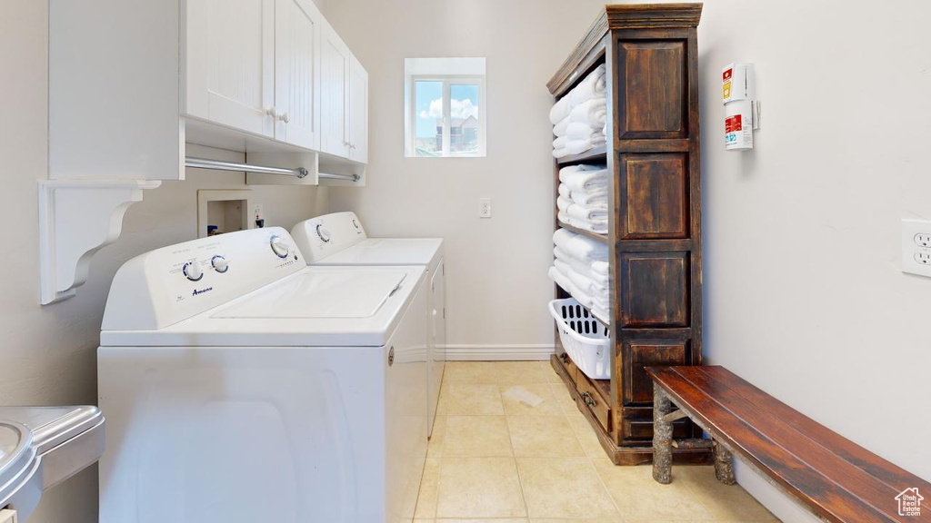 Laundry area featuring cabinets, washer hookup, light tile floors, and washing machine and clothes dryer