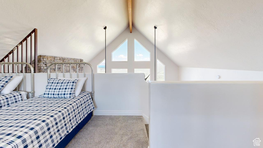 Carpeted bedroom with vaulted ceiling with beams