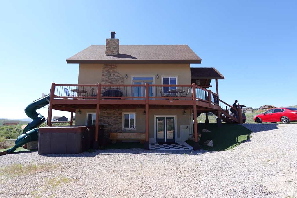 Back of house with a playground, a deck, and french doors