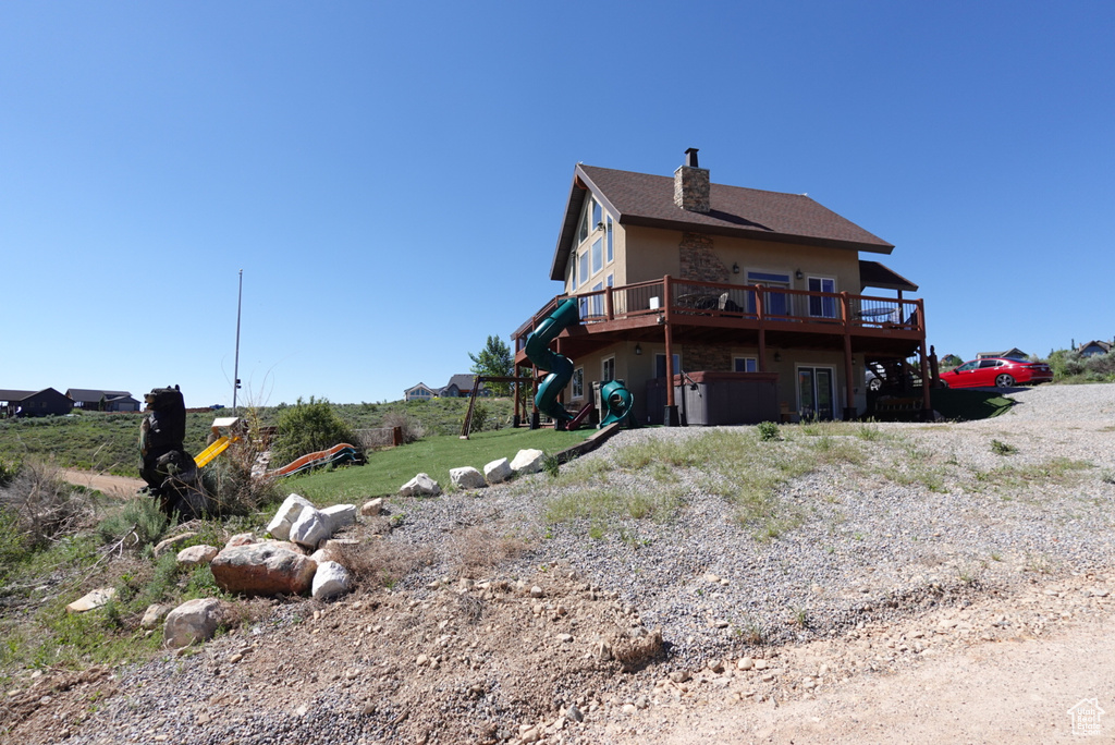 Rear view of property with a playground and a deck