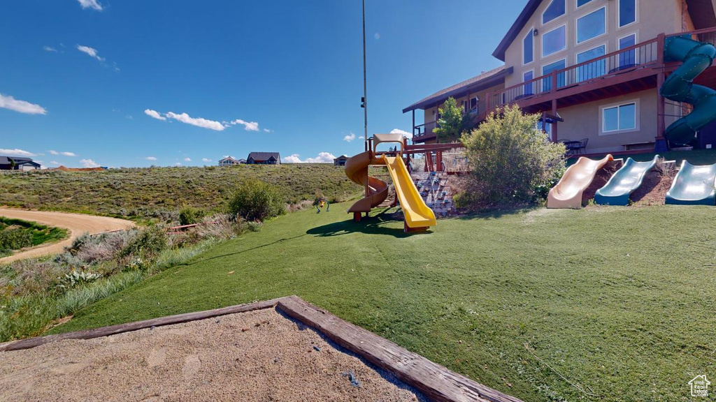 View of yard with a playground and a balcony