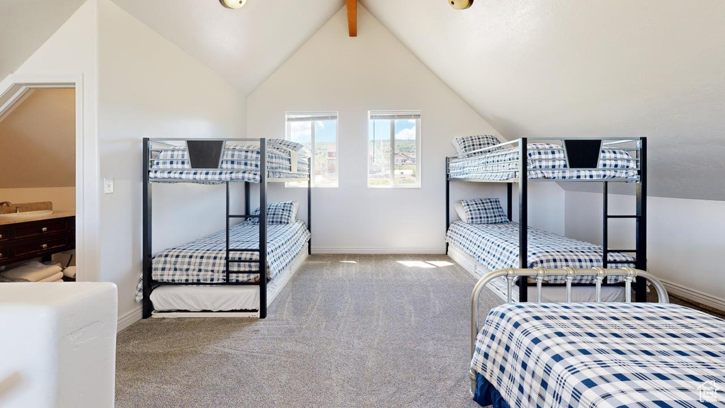 Carpeted bedroom with sink and vaulted ceiling